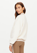 THE UPSIDE womens white varsity Banks Bomber jacket made with recycled sherpa features welt pockets, rib stripe detail at neck and cuffs and snap buttons.