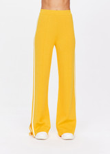 THE UPSIDE women's yellow Dunes Freya Knit Pant is a straight leg pant with an elasticated waistband for comfort and white side stripes. Designed to wear for recovery and leisure.