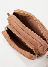 THE UPSIDE women's tan recycled fabric Odyssey Crossbody Bag features an adjustable and removable strap, multiple zippered pockets and silver hardware.