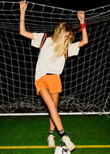 THE UPSIDE women's orange recycled fabric Elixir Lucky Run Short is designed for a relaxed fit and features an elasticated waistband and curved hem. Ideal for running.