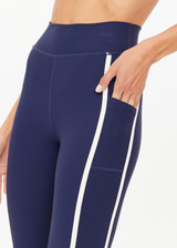 THE UPSIDE women's navy recycled peached Samara 25inch Legging is a soft & supportive fit and features side pockets and contrast cream stripes with curved hem detail. Made for pilates.