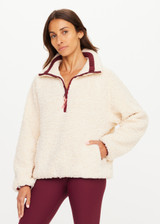 THE UPSIDE women's natural recycled polyester Harlow Fleece Pullover has a relaxed fit with a striped rib collar, contrast maroon stripes, and zip pockets. Made for lifestyle