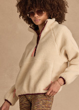 THE UPSIDE women's natural recycled polyester Harlow Fleece Pullover has a relaxed fit with a striped rib collar, contrast maroon stripes, and zip pockets. Made for lifestyle