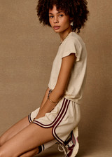 THE UPSIDE women's cream Klio Short is designed for a mid-rise, relaxed fit and features a soft elasticated waistband with drawcord and contrast binds in maroon along curved hem. Made for everyday.