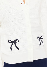THE UPSIDE women's cream Jolie Isabeli Knit Cardigan is a regular fit with a blouson sleeve crafted from a pointelle knit and features navy embroidered bows. Made for tennis, golf & pickleball.