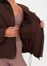 THE UPSIDE women's brown Mercer Hooded Puffer Jacket is fully lined and features invisible zip pockets with fleece lining, soft elasticated cuffs, a hood and is made from recycled fabric. Made for lifestyle.