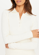 THE UPSIDE women’s cream recycled Cruz Collared Polo is long sleeved with a ribbed collar and moisture wicking fabrication. Made for running.