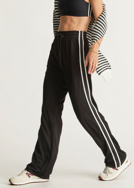 THE UPSIDE women's black Celeste Pant is a relaxed fit, mid rise trackpant with a slinky fabrication. It features a straight leg silhouette, elasticated waistband and drawcord, knitted striped tape down side seams and pockets at the front and back.