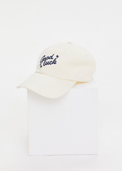 THE UPSIDE women’s cream Good Luck Soft Cap features an embroided 'Good Luck' on front with an adjustable strap at the back.