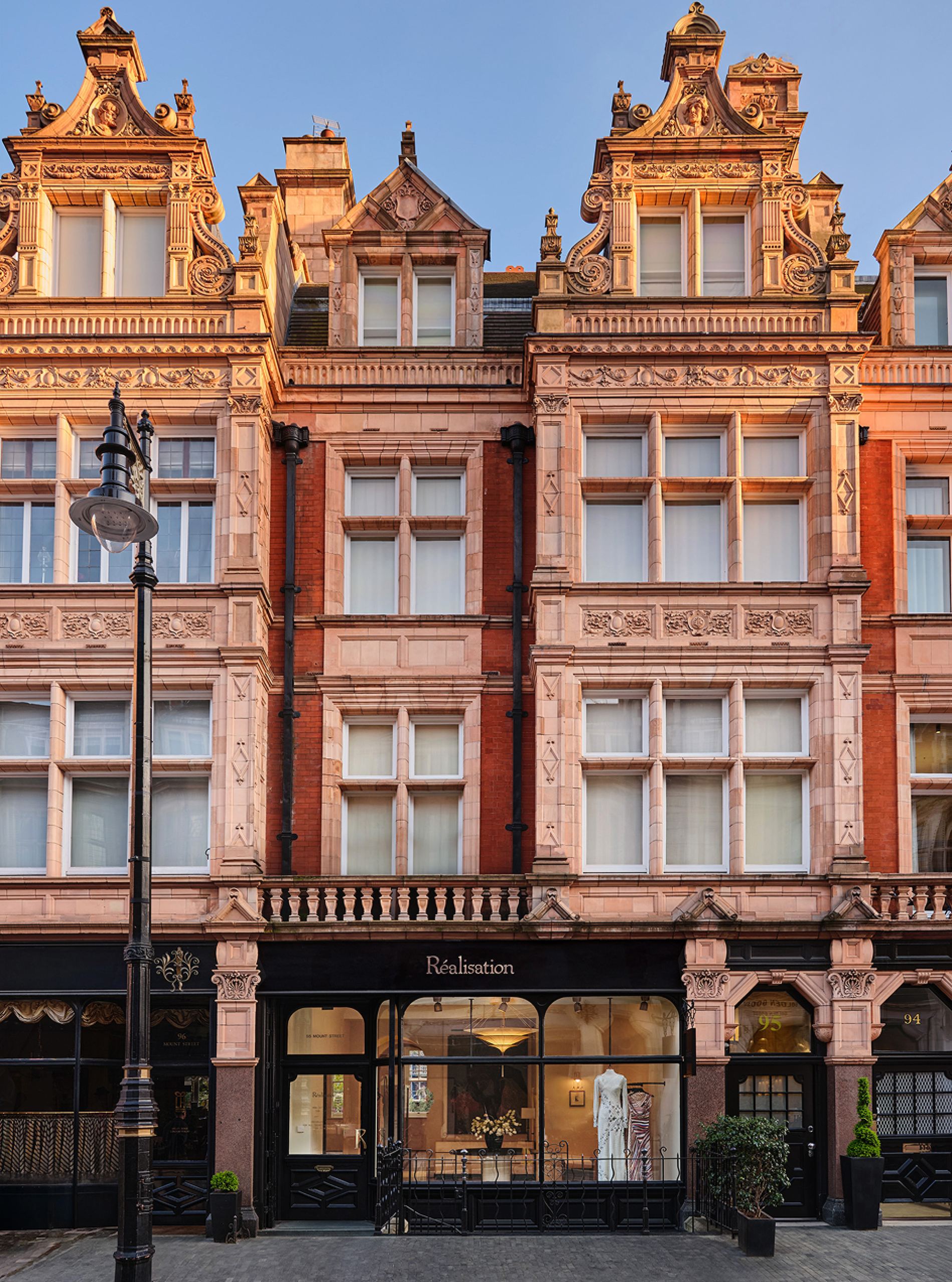 Red-brick façade of the Réalisation Par store at 95 Mount Street, with a white dress in the window