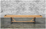 Venture Shuffleboard Astoria Sport Shuffleboard Table, wooden sports shuffleboard table with black metal legs against a brick wall background.