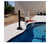 First Team Inc First Team HYDROCHAMP Adjustable Pool Side Basketball Hoop, mounted beside a swimming pool with a clear backboard and red hoop for recreational water basketball.