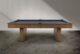 Doc & Holliday The Slater Slate Pool Table, wooden pool table in minimalist design with a blue playing surface, placed on a concrete floor against a white wall.