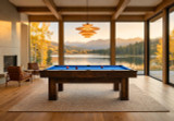Doc & Holliday Maverick Rustic Slate Pool Table – Buffalo Nickel Rail Sights, in a modern room with large windows overlooking a lake and mountain landscape.