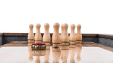 Plank & Hide Co Plank & Hide Shuffleboard Bowling Pin Set, wooden shuffleboard pins arranged on a game table with a puck in front, game equipment for shuffleboard and bowling.
