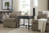 Hooker Furniture Ciao Bella Rectangular End Table, a stylish black wood side table with a single drawer and turned legs, placed between two beige armchairs in a cozy living room setting.