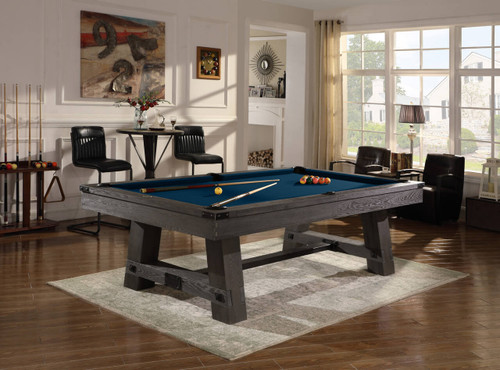Playcraft Yukon Slate Pool Table by Playcraft, weathered Fieldstone or Northern Drift finish, in a well-lit living room with large windows, black chairs, and decorative wall art.