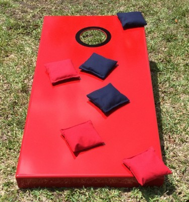 Sawyer Twain All Weather Outdoor Ultimate Cornhole, red cornhole game with nylon bags laid on a grassy surface.