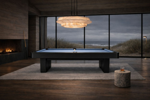 Doc & Holliday Derby Slate Pool Table in Black Maple, modern pool table with black frame and slate surface in a stylish room with large windows and ocean view.