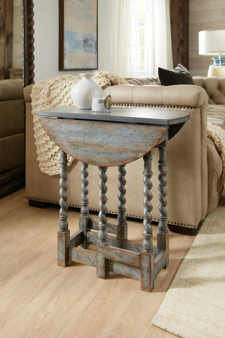 Hooker Furniture Sabi Sands Sling Chair, rustic wooden side table with a distressed finish, cream-colored sofa with nailhead trim, decorative vases, and cozy knitted blanket in a bright living room.