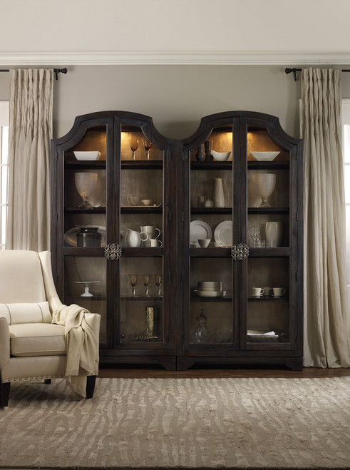 Hooker Furniture Sanctuary Glass Bunching Curio-Ebony Antiqued Oak, a dark wooden display cabinet with glass doors showcasing fine china and glassware, in a living room setting.