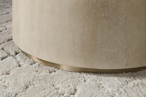 Hooker Furniture Cascade Cocktail Table, close-up image showcasing the light-colored wood finish and rounded edge design sitting on a plush, cream-colored rug.