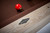 Brunswick Billiards Brunswick Matanza Slate Pool Table - Sandwash Finish, close-up of the wood grain and brand logo on the side of the table with a pool ball nearby.