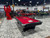 Brunswick Billiards Brunswick Black Wolf Slate Pool Table, red felt surface with pool cues, snooker accessories, and a scorekeeper on top, situated in a high-end car showroom with luxury sports cars in the background.
