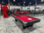 Brunswick Billiards Brunswick Black Wolf Slate Pool Table, red felt with cues, in an automotive museum setting.