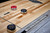 Brunswick Billiards Brunswick Sanibel Shuffleboard Table | Rustic Grey, showcasing the wooden surface with shuffleboard pucks and a control panel.