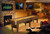 Brunswick Billiards Brunswick Andover II Shuffleboard Table, rustic dark brown finish, 12 or 14 feet length, in a cozy living room with stone fireplace and wood-paneled walls.