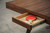 Plank & Hide Co Plank & Hide Harper Table Tennis Table with Storage Drawer, showing a close-up of the wooden table surface with the storage drawer pulled out containing a red ping pong paddle and ball.