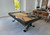 Plank & Hide Co Axton Steel Pool Table, modern indoor pool table with beige felt top, black frame, and pool cues placed on it, in a contemporary home game room.