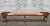 Venture Shuffleboard Grand Deluxe Sport Shuffleboard Table by Venture, made in USA, showing a full-length wooden shuffleboard table with a natural wood finish and black bumpers, set against a brick wall background.