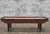 Venture Shuffleboard 9' Classic Bank Shot Shuffleboard, a custom-made indoor shuffleboard table with a wooden finish and red pucks, made in the USA.
