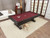 Playcraft Brazos River 8' Slate Pool Table with Weathered Black Finish, billiards table with red felt in a modern living room setting, featuring a pool ball rack, cue ball, and a dog lying underneath.