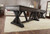 Playcraft Brazos Shuffleboard Table in Weathered Black, 12, 14, 16 feet, showcasing a long, stylish shuffleboard table in a modern living room setting with a beige carpet and wooden floor.