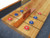 Playcraft Telluride Honey Shuffleboard Table with optional Overhead Electronic Scoring, showcasing a wooden surface with blue and red pucks and a central divider.