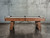 Plank & Hide Co Isaac Slate Pool Table, distressed brown and gold finish with wooden legs and modern design, set against a concrete wall background.