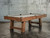 Plank & Hide Co Isaac Slate Pool Table by Plank & Hide, with distressed brown wood finish and gold accents, set against a concrete wall background.
