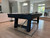 Plank & Hide Co Isaac Pool Table Distressed Black & Gold, in a modern living space with large windows and light wood flooring.