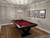 Doc & Holliday Savant 8' Slate Pool Table | Brown Sugar Finish, inside view of a stylish game room with a pool table, modern artwork, and a geometric chandelier.