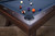 Doc & Holliday George Slate Pool Table in Antique Coffee, featuring a dark wood finish, green pool table felt, and multicolored billiard balls on the playing surface.
