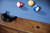 Doc & Holliday Churchill Slate Pool Table with Dining Top Option, close-up view showing wooden edge and scattered small debris on the table.