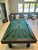 Doc & Holliday Zurich Pool Table by Doc & Holliday with black finish and custom details, positioned in a cozy lounge area with seating and large windows.