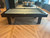 Zurich Slate Pool Table by Doc & Holliday in matte black with gray felt and bold Parsons-style legs. Modern luxury billiards table staged in a contemporary office lounge with hardwood floors. Zurich Slate Pool Table by Doc & Holliday in matte black with gray felt and bold Parsons-style legs. Modern luxury billiards table staged in a contemporary office lounge with hardwood floors.