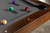 Doc & Holliday Scholar Pool Table by Doc & Holliday, showcasing a close-up view of the table with billiard balls on the slate surface and a wooden finish.