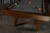 Doc & Holliday Scholar Pool Table in Pecan, with a wooden frame, black pockets, and gray playing surface, set up for billiards.