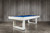 Doc & Holliday Santorini Pool Table, modern white pool table with blue playing surface, sleek design, in a room with grey wooden wall and concrete floor