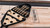Plank & Hide Co Lana Pool Table & Shuffleboard Combo, image showing accessories in a black carrying case on a wooden pool and shuffleboard table with the Plank & Hide logo.